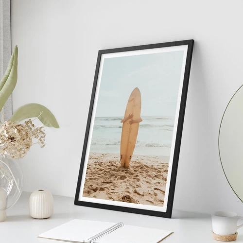 Plakat w czarnej ramie - Z miłości do fal - Osoba trzymająca deskę surfingową na plaży, z widokiem na morze - 50x70cm